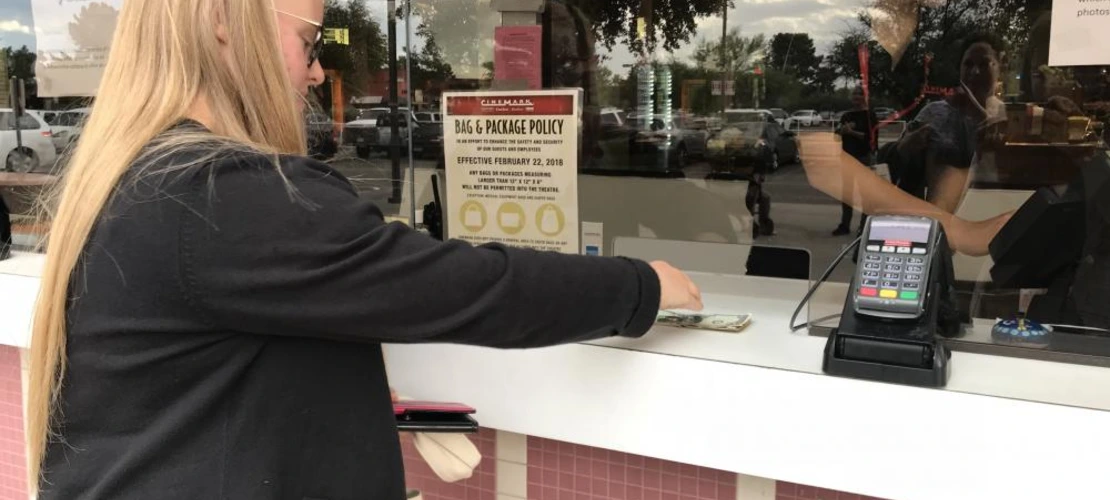 female student paying for movie ticket